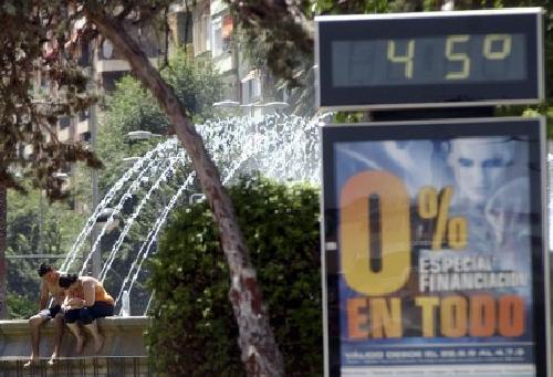 Dos jvenes se refrescanen la fuente de la plaza circular de Murcia cerca de un temmetro de ambiente que marca 45 grados centigrados, coincidiendo con la entrada en alerta amarilla debido a las altas temperaturas. EFE