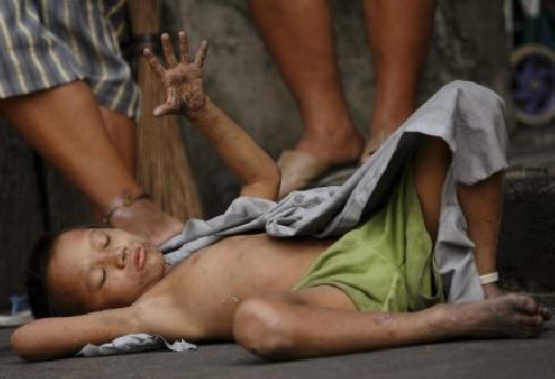 Un nio mendigo descansa en el suelo mientras esperan su racin de sopa en un comedor social Manila (Filipinas.