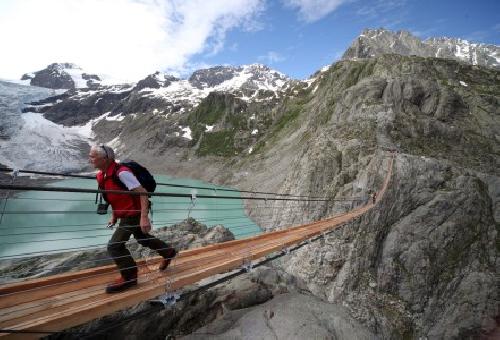 Montaeros cruzan el puente colgante sobre el lago Trift, en el glaciar Trift de la cadena montaosa de Susten, en Suiza. El puente tiene una altura de 100 metros y una longitud de 170 metros.